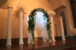 Wedding Ceremony: White Arch with greenery, lights, white flowers and fabric. Fluted Columns, white urns and white feathers @ UAW Hall in Spring Hill, TN